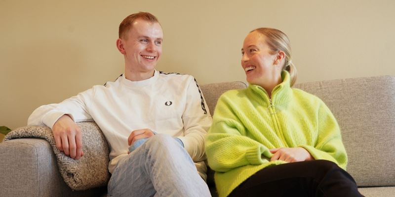 Asle Liland og Margrethe Hafte smiler fornøyd, bilde fra sofaen hjemme i huset deres.
